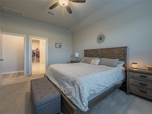 carpeted bedroom with ceiling fan, lofted ceiling, a spacious closet, and a closet