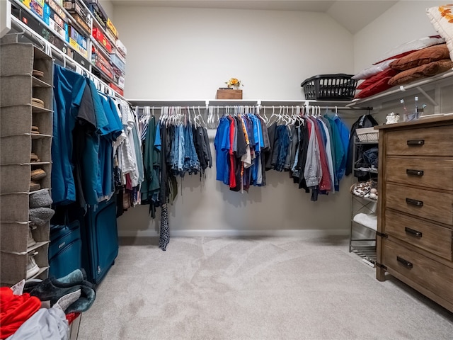 walk in closet with light carpet and lofted ceiling