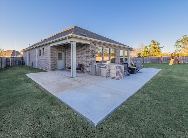 rear view of house with a playground, a patio area, a yard, and exterior kitchen