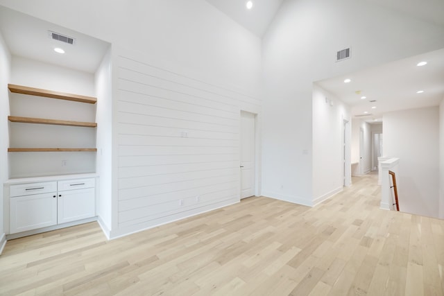 unfurnished living room featuring high vaulted ceiling and light wood-type flooring