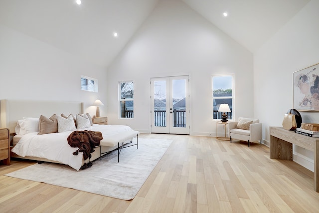 bedroom featuring a towering ceiling, access to exterior, light hardwood / wood-style floors, and french doors