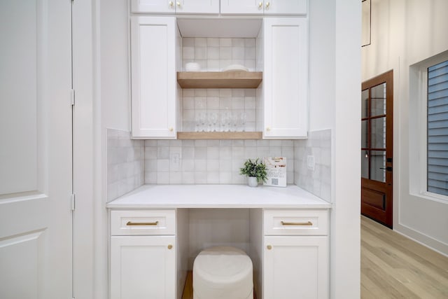 bar with backsplash, light hardwood / wood-style floors, and white cabinets