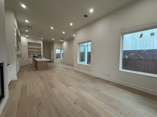 unfurnished living room with sink and light hardwood / wood-style flooring