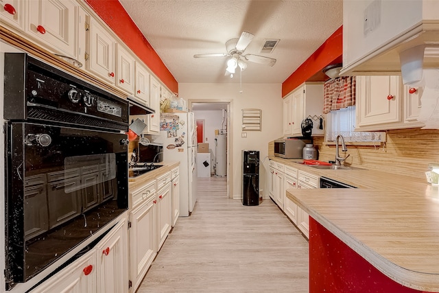 kitchen featuring sink, light wood-type flooring, a textured ceiling, tasteful backsplash, and black oven