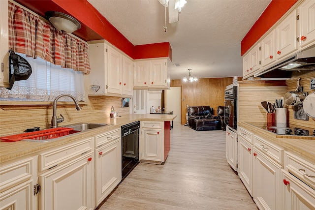 kitchen with white cabinetry, sink, light hardwood / wood-style flooring, wooden walls, and black appliances