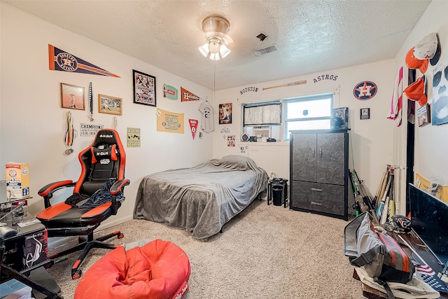 carpeted bedroom featuring ceiling fan and a textured ceiling