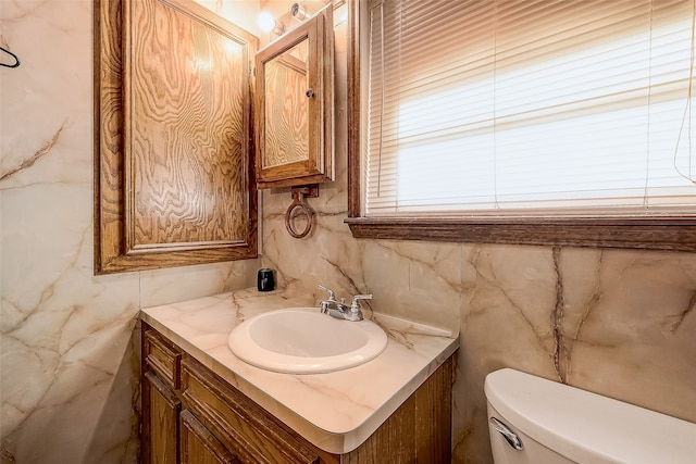 bathroom featuring vanity, toilet, and tile walls