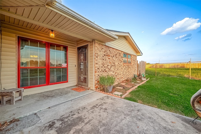 view of exterior entry with a lawn and a patio area