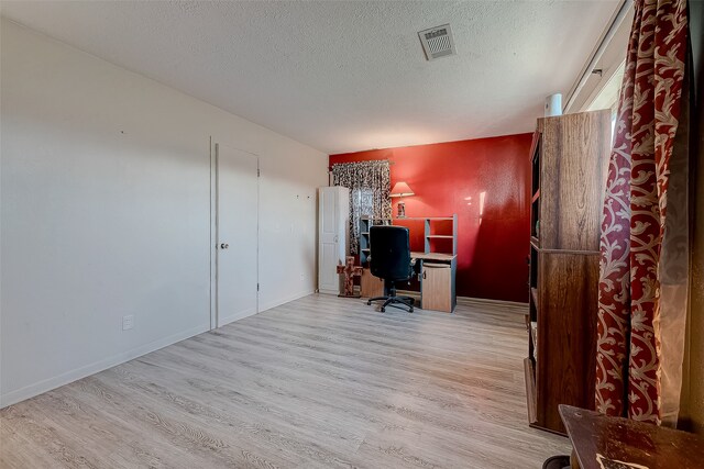 office area with light hardwood / wood-style floors and a textured ceiling