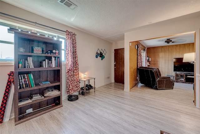 living room with a textured ceiling, light wood-type flooring, plenty of natural light, and ceiling fan