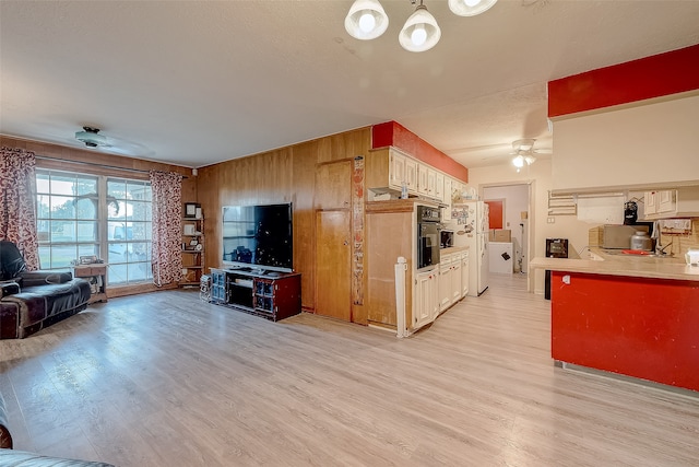 living room featuring ceiling fan, light hardwood / wood-style floors, and wooden walls