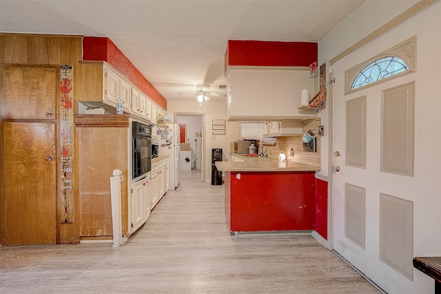 kitchen with black oven, ceiling fan, light hardwood / wood-style floors, and a textured ceiling