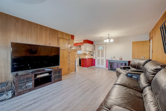 living room featuring wooden walls, light hardwood / wood-style flooring, and a chandelier