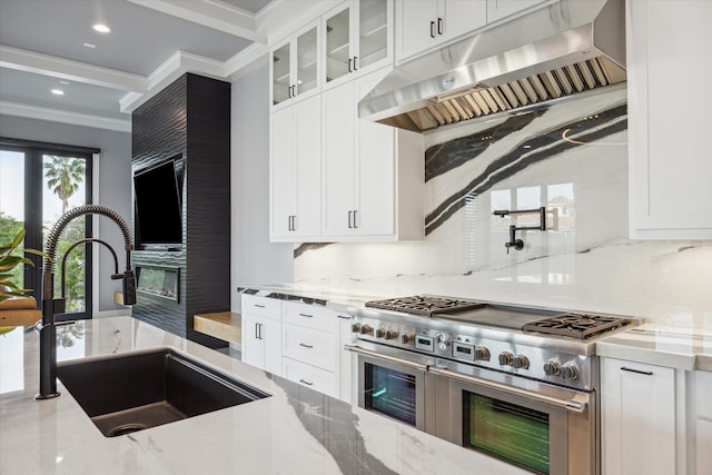 kitchen featuring light stone countertops, white cabinetry, range with two ovens, and crown molding