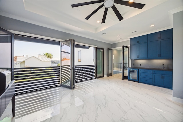 kitchen with a raised ceiling, sink, blue cabinetry, and beverage cooler