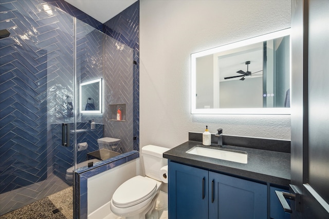 bathroom with vanity, a shower with door, toilet, and ceiling fan