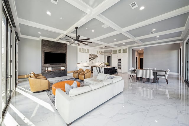 living room featuring coffered ceiling, sink, ceiling fan, a fireplace, and beamed ceiling