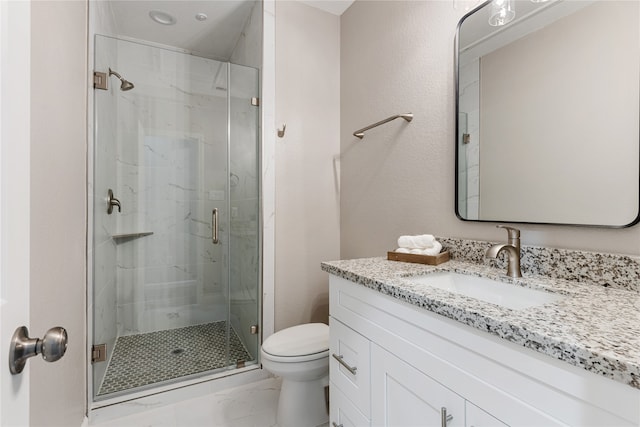 bathroom featuring a shower with door, vanity, and toilet