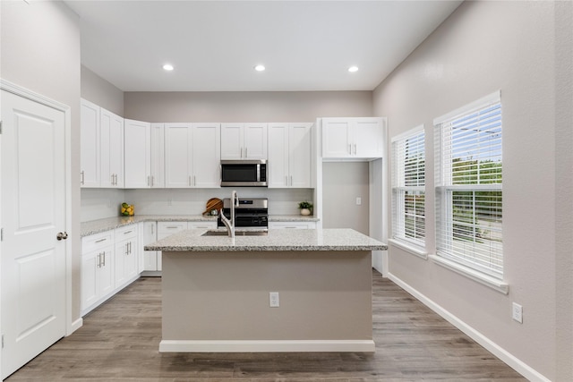 kitchen featuring appliances with stainless steel finishes, white cabinets, and light stone countertops