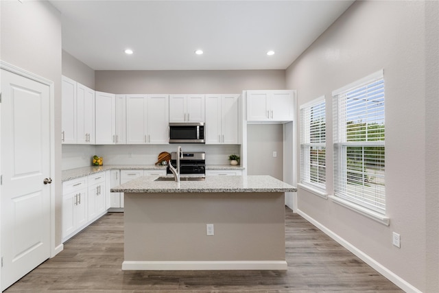 1321 E 35th St, Houston, TX 77022 - kitchen featuring appliances with stainless steel finishes, a sink, white cabinets, a kitchen island with sink, and recessed lighting