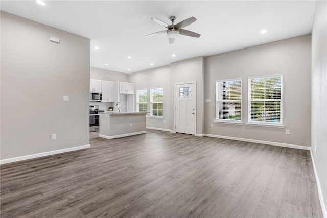 unfurnished living room featuring ceiling fan, sink, and dark wood-type flooring