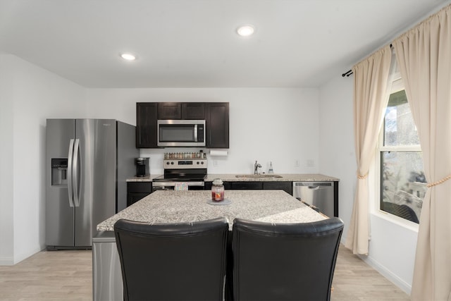 kitchen featuring light wood-type flooring, appliances with stainless steel finishes, a center island, and sink