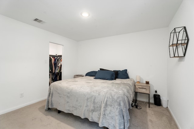 bedroom featuring a walk in closet, light colored carpet, and a closet