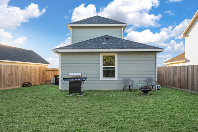 back of property with a lawn and an outdoor fire pit