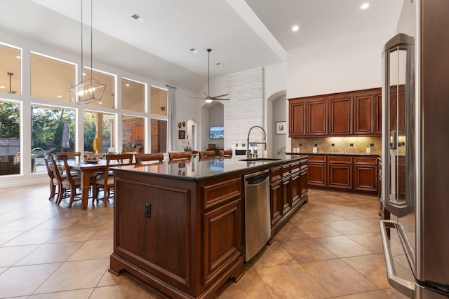 kitchen featuring decorative light fixtures, a center island with sink, stainless steel appliances, and sink