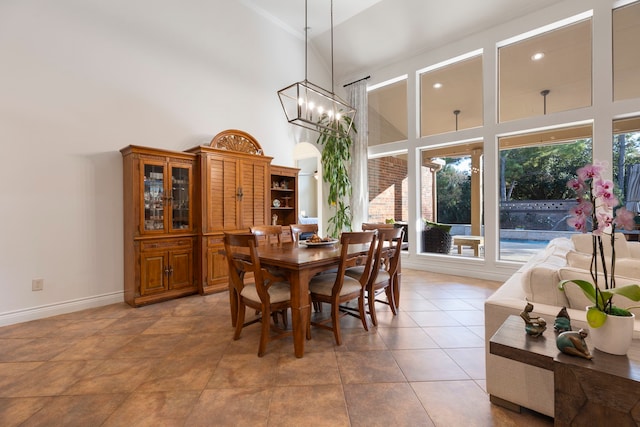 dining space with a notable chandelier, high vaulted ceiling, a wealth of natural light, and tile patterned flooring