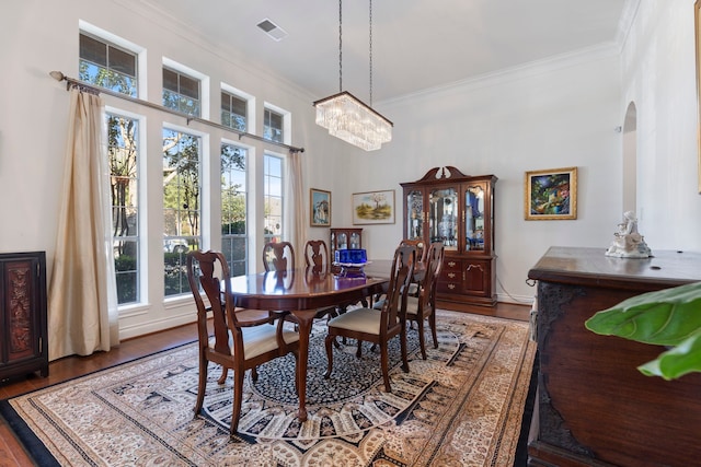 dining room with hardwood / wood-style flooring, an inviting chandelier, and crown molding