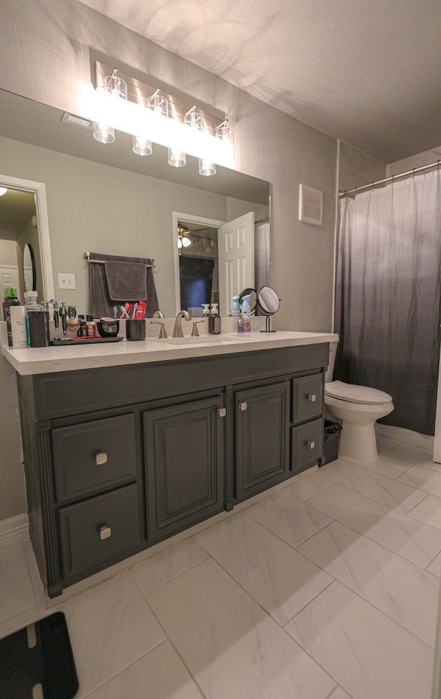 bathroom with vanity, toilet, and a textured ceiling