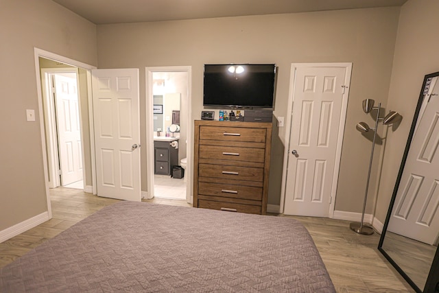 bedroom featuring ensuite bathroom and light wood-type flooring