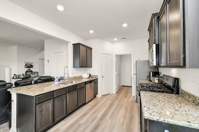 kitchen featuring dark brown cabinetry, light stone countertops, sink, stainless steel appliances, and light wood-type flooring