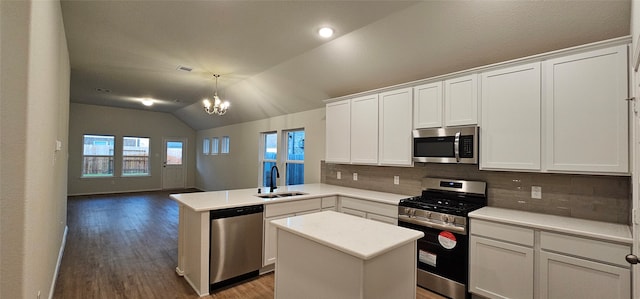 kitchen featuring kitchen peninsula, stainless steel appliances, sink, a center island, and lofted ceiling