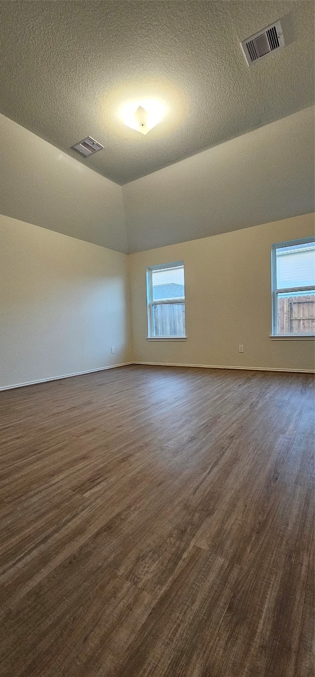 bonus room with a textured ceiling, dark hardwood / wood-style floors, and vaulted ceiling