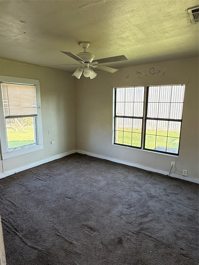 spare room with dark colored carpet, a textured ceiling, and ceiling fan