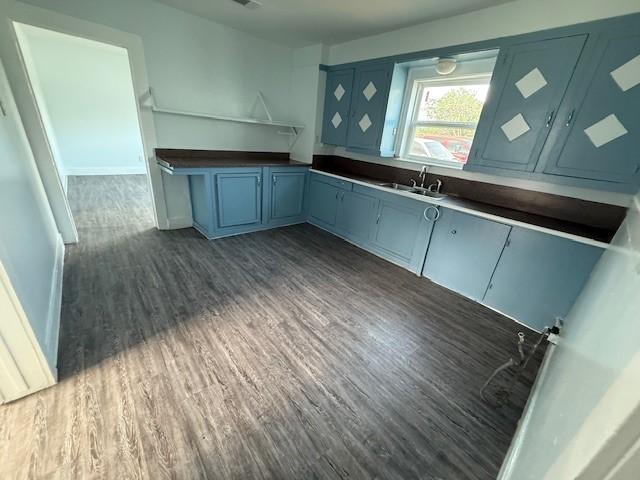 4822 W Cedar Bayou Lynchburg Rd, Baytown, TX 77521 - kitchen with a sink, blue cabinets, dark wood-style flooring, dark countertops, and baseboards