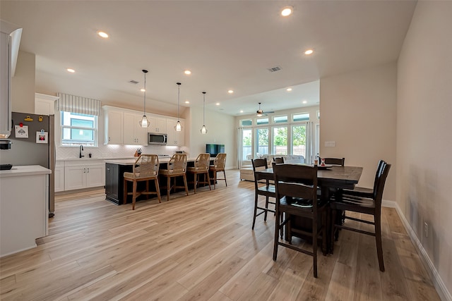 dining room with light hardwood / wood-style flooring, a wealth of natural light, and ceiling fan