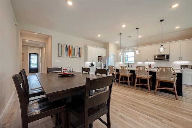 dining space with sink and light wood-type flooring