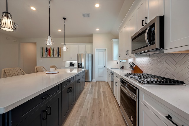 kitchen featuring hanging light fixtures, sink, stainless steel appliances, and a breakfast bar area