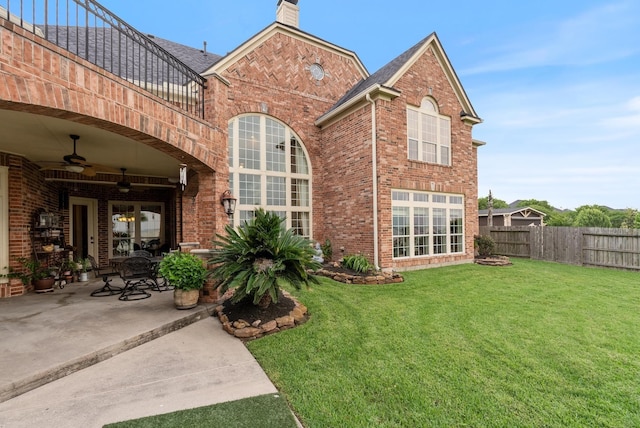 rear view of house featuring a lawn, ceiling fan, a balcony, and a patio