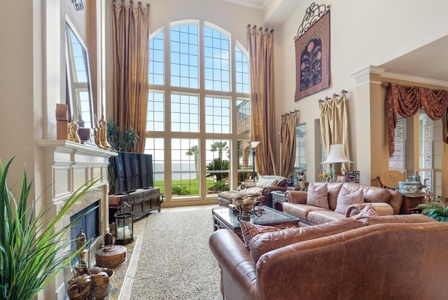 living room with a fireplace, a healthy amount of sunlight, ornamental molding, and a high ceiling