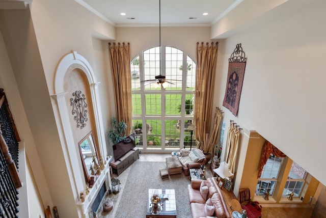 living room featuring ceiling fan, a high ceiling, and ornamental molding