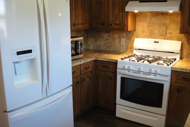 kitchen with tasteful backsplash, dark hardwood / wood-style flooring, extractor fan, and white appliances