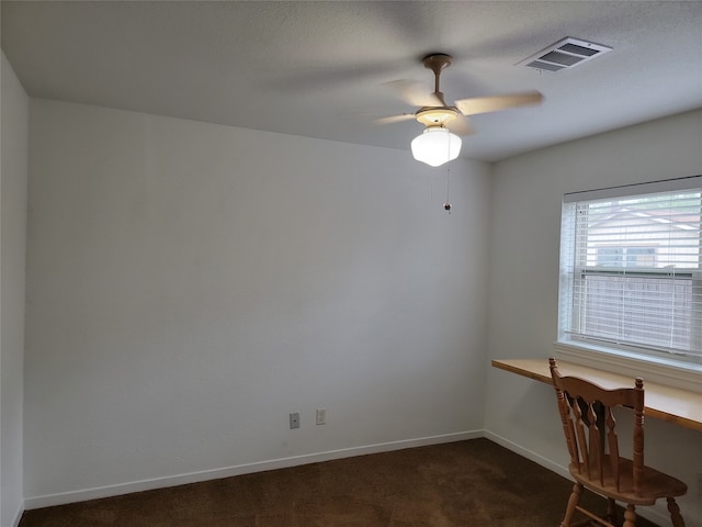 unfurnished office featuring ceiling fan and dark carpet