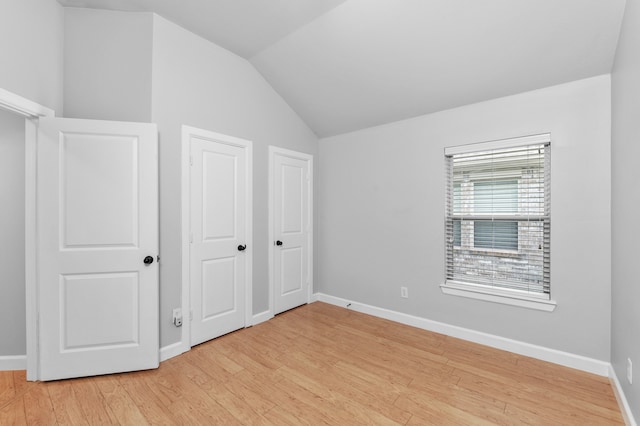 unfurnished bedroom with lofted ceiling and light wood-type flooring