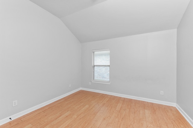 spare room with light hardwood / wood-style floors and lofted ceiling