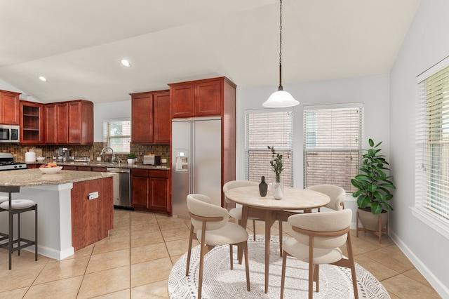 kitchen with a center island, a healthy amount of sunlight, pendant lighting, lofted ceiling, and appliances with stainless steel finishes