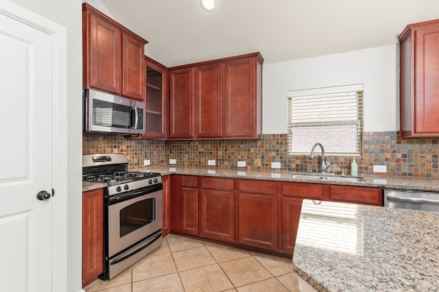 kitchen featuring sink, decorative backsplash, light stone countertops, light tile patterned flooring, and stainless steel appliances